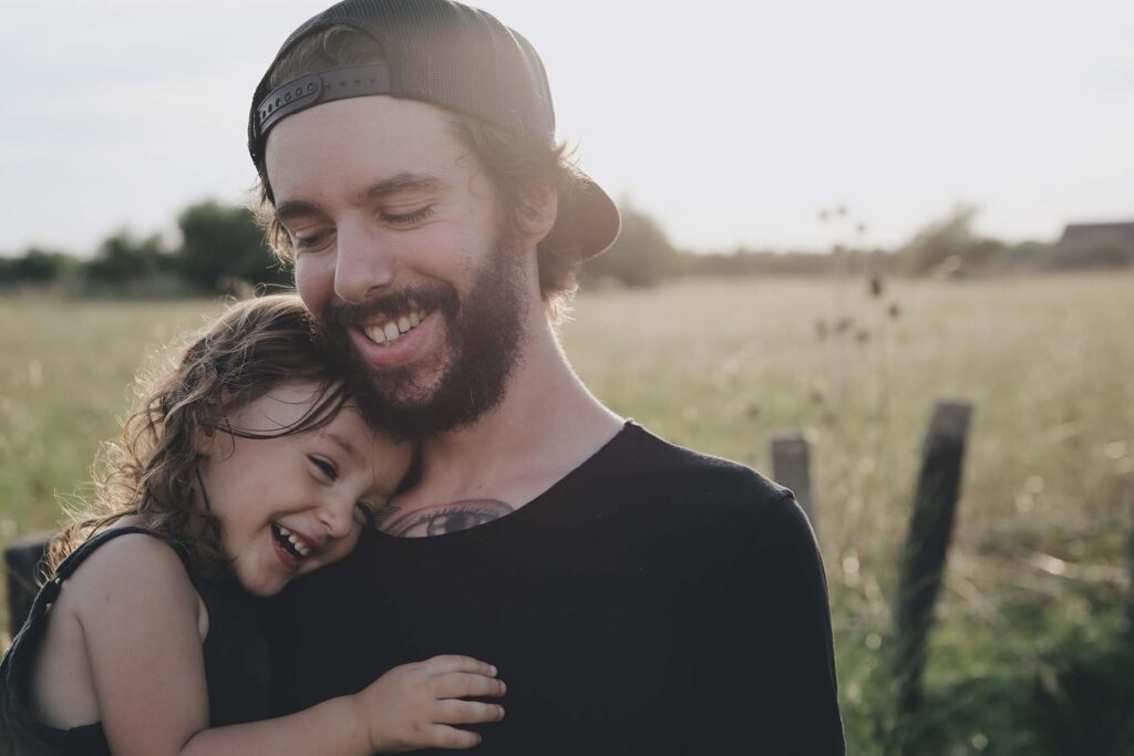 father holding his young daughter, both smiling